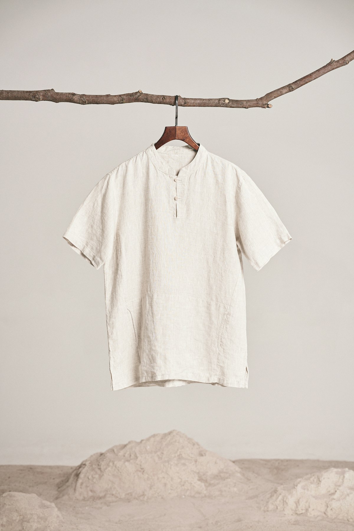 Chemise légère en lin beige à manches courtes suspendue à un cintre en bois