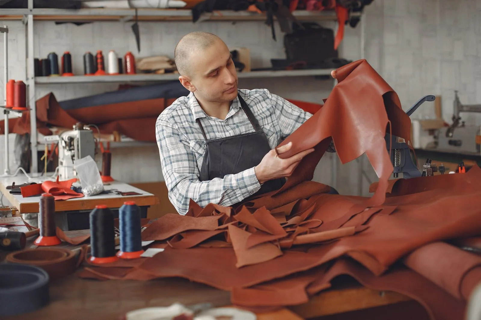 Artisan examinant une peau de cuir a la lumiere dans un atelier