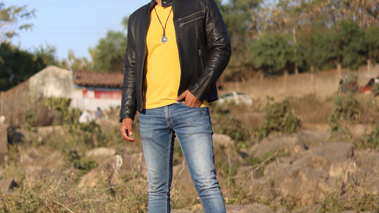 Homme stylise portant un jean droit avec veste en cuir et t-shirt jaune