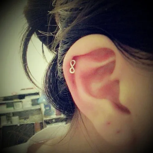Ear wearing a piercing jewel on the helix, the starting point of a multi-piece ear composition