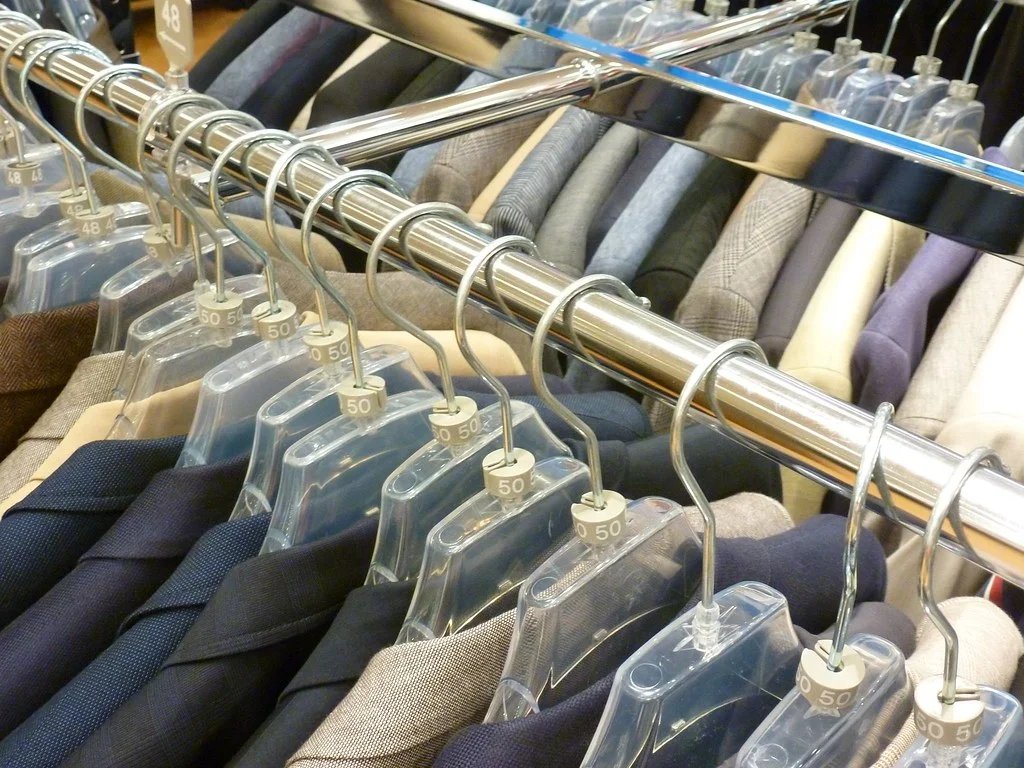 Men's suit jackets lined up on a rack in store