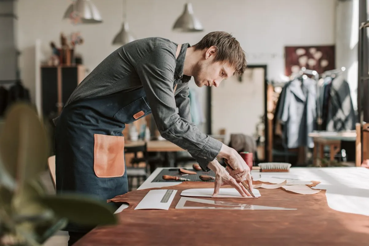 Artisan coupant une peau de cuir a la main dans un atelier
