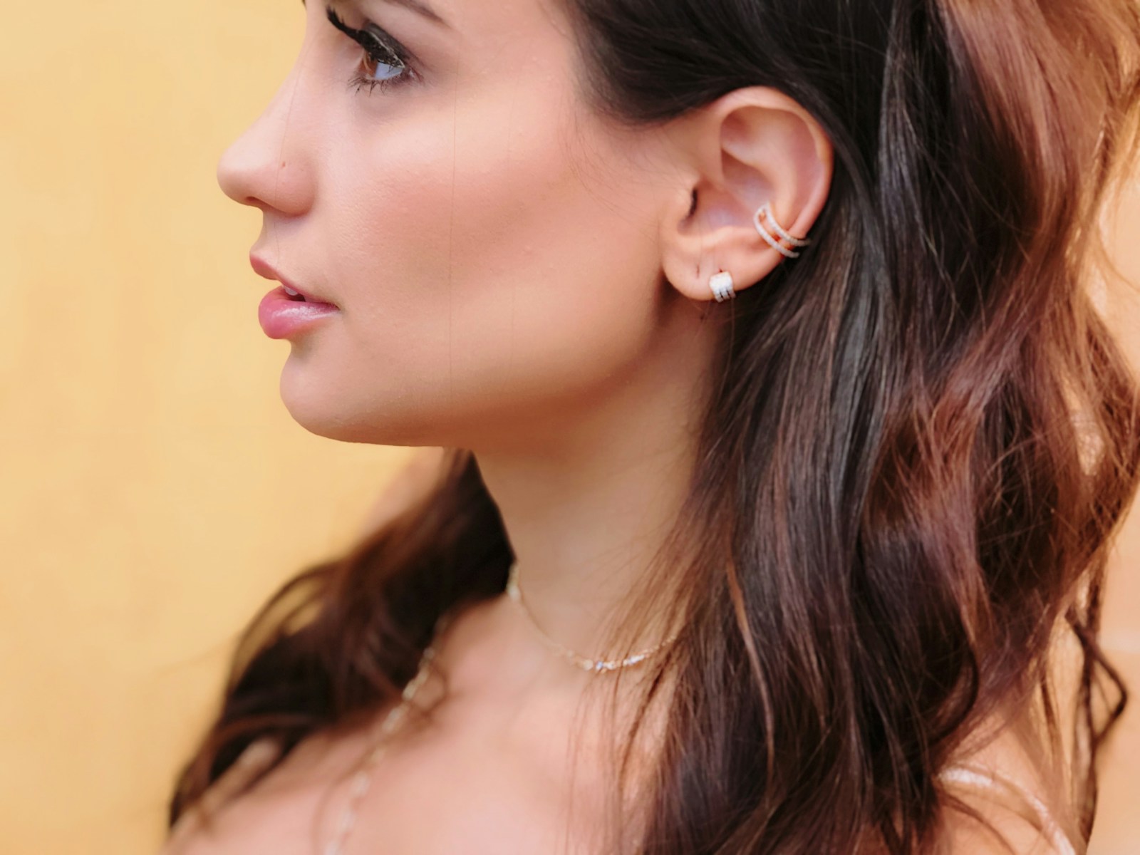 Femme aux cheveux longs portant un collier et des boucles d'oreilles, piercing conch
