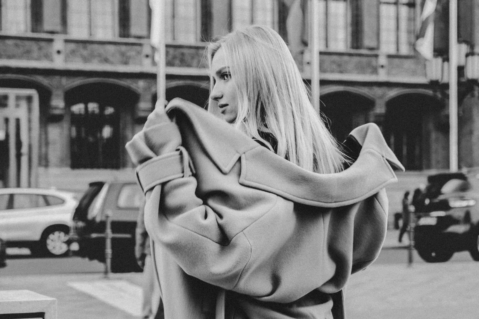 Femme en manteau de laine oversize à grand col dans une rue, photo en noir et blanc