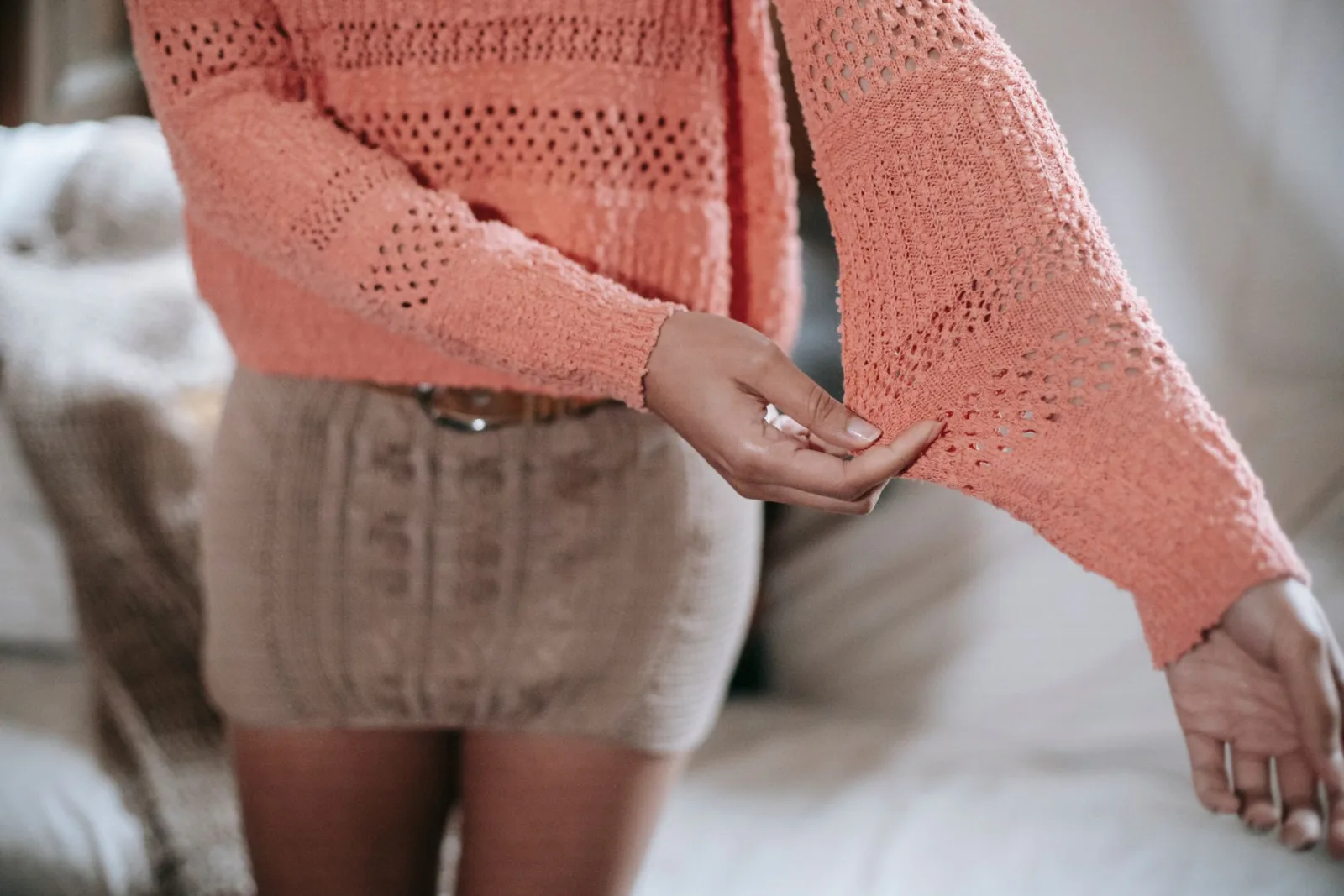 Gros plan sur une femme portant un pull en maille ajourée corail
