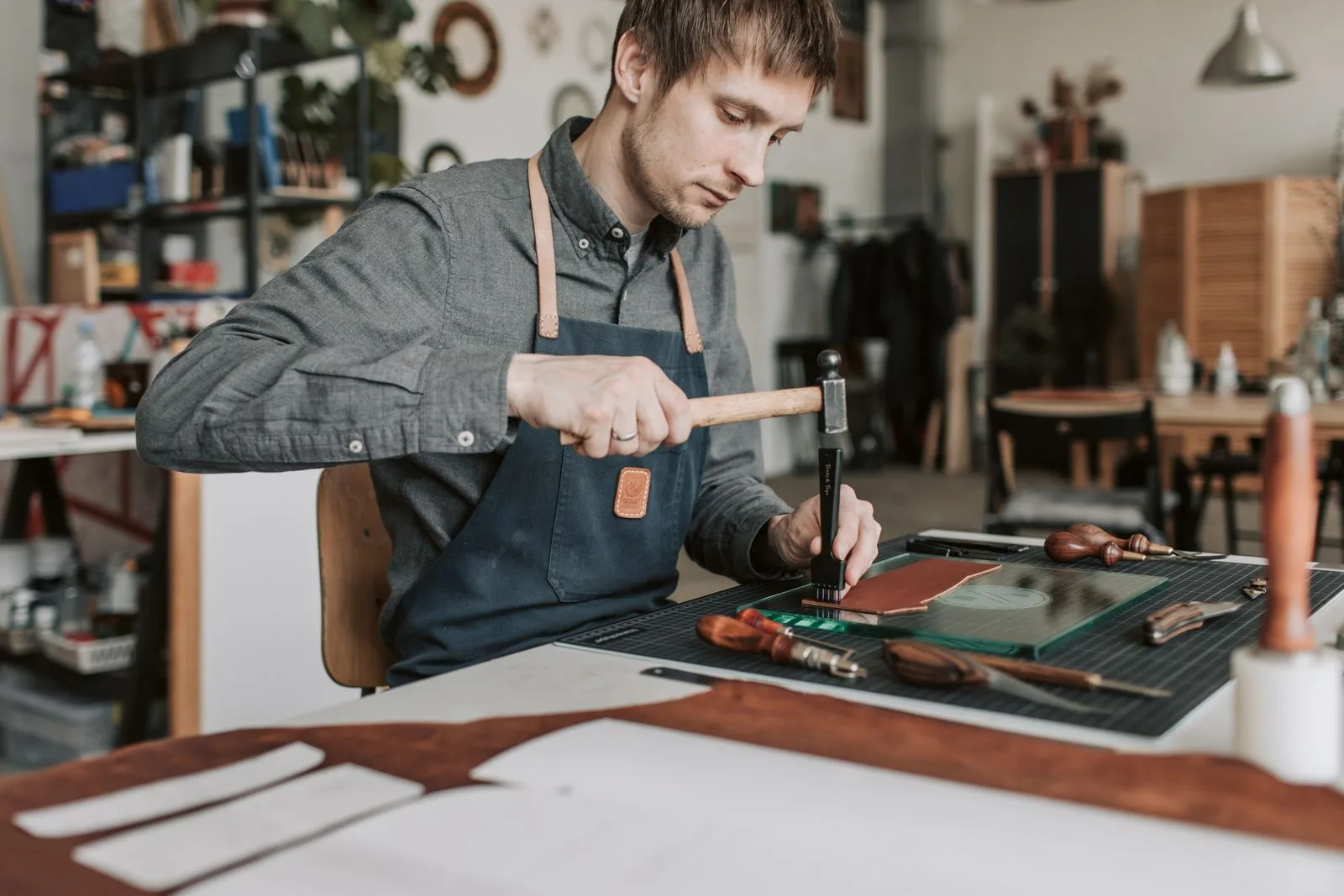 Artisan faconnant une piece de cuir a la main avec ses outils