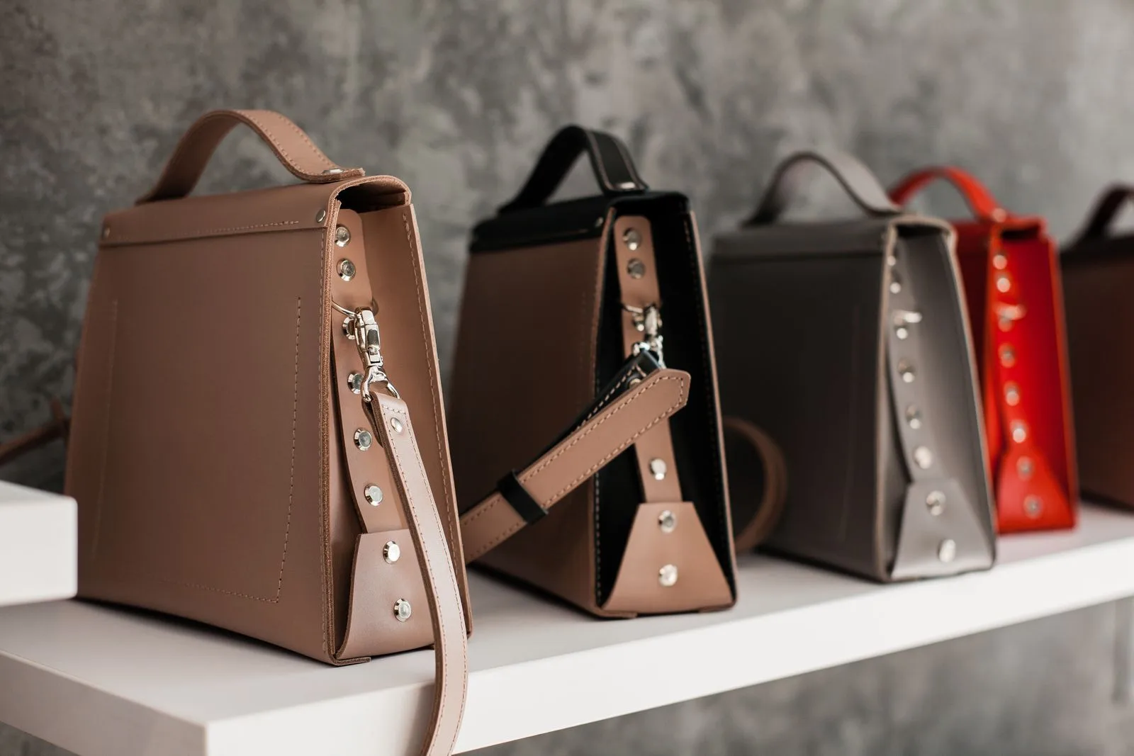 Sacs en cuir de créateurs alignés sur une étagère blanche