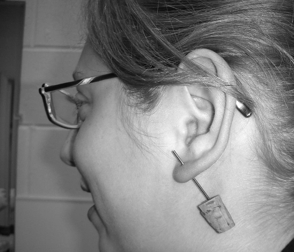 Ear with several titanium piercings on the lobe and cartilage