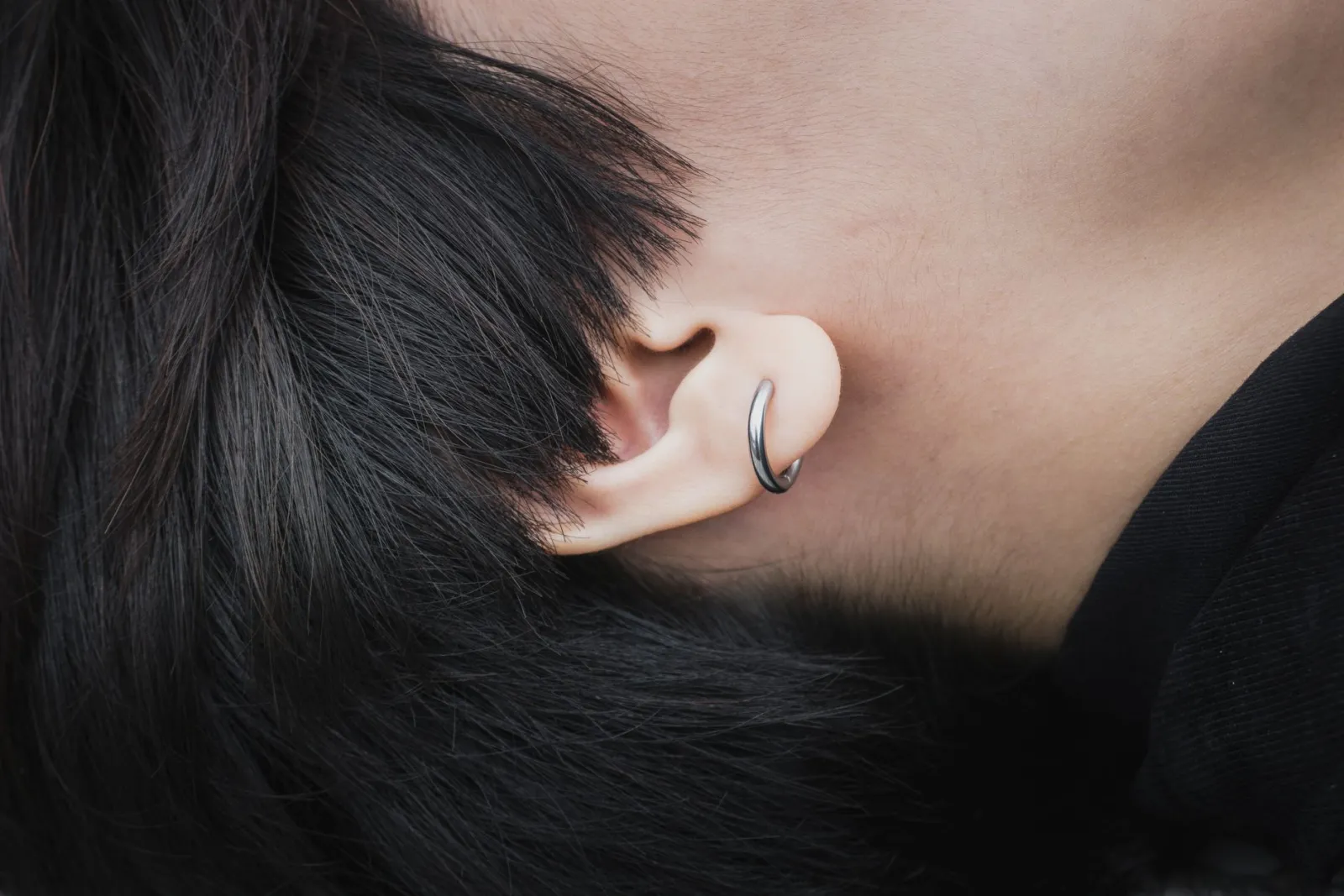 Gros plan sur une oreille portant un anneau de piercing argenté fin et minimaliste