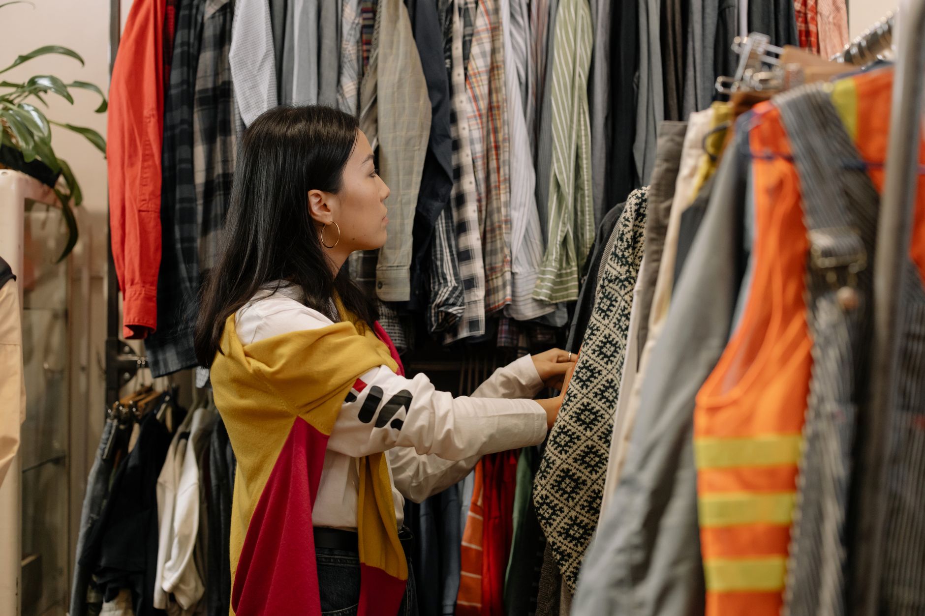 Jeune femme examinant des vêtements sur un portant dans une friperie
